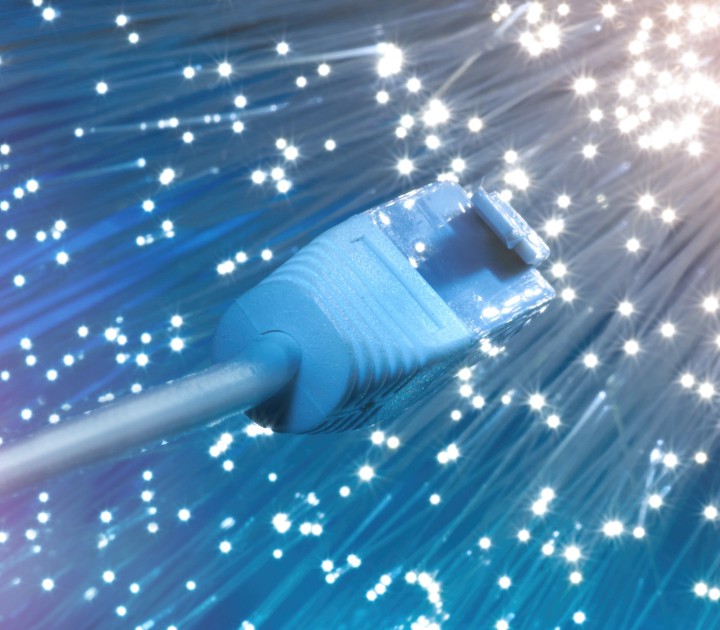 Futuristic technological background, closeup on the end of optical fiber network cable on blue background
